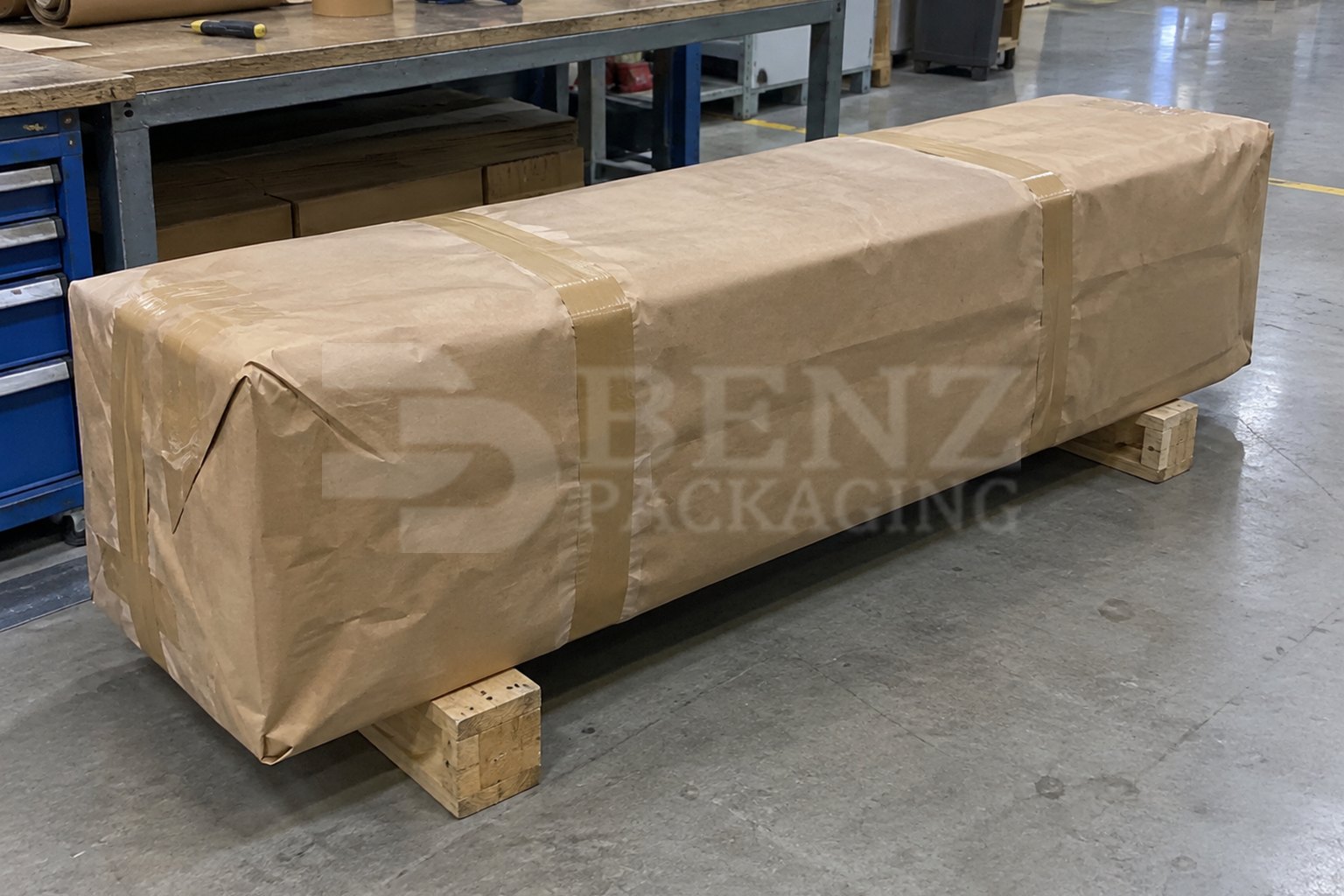 Long gearbox-shaped load fully enclosed in brown VCI plain paper on timber skids