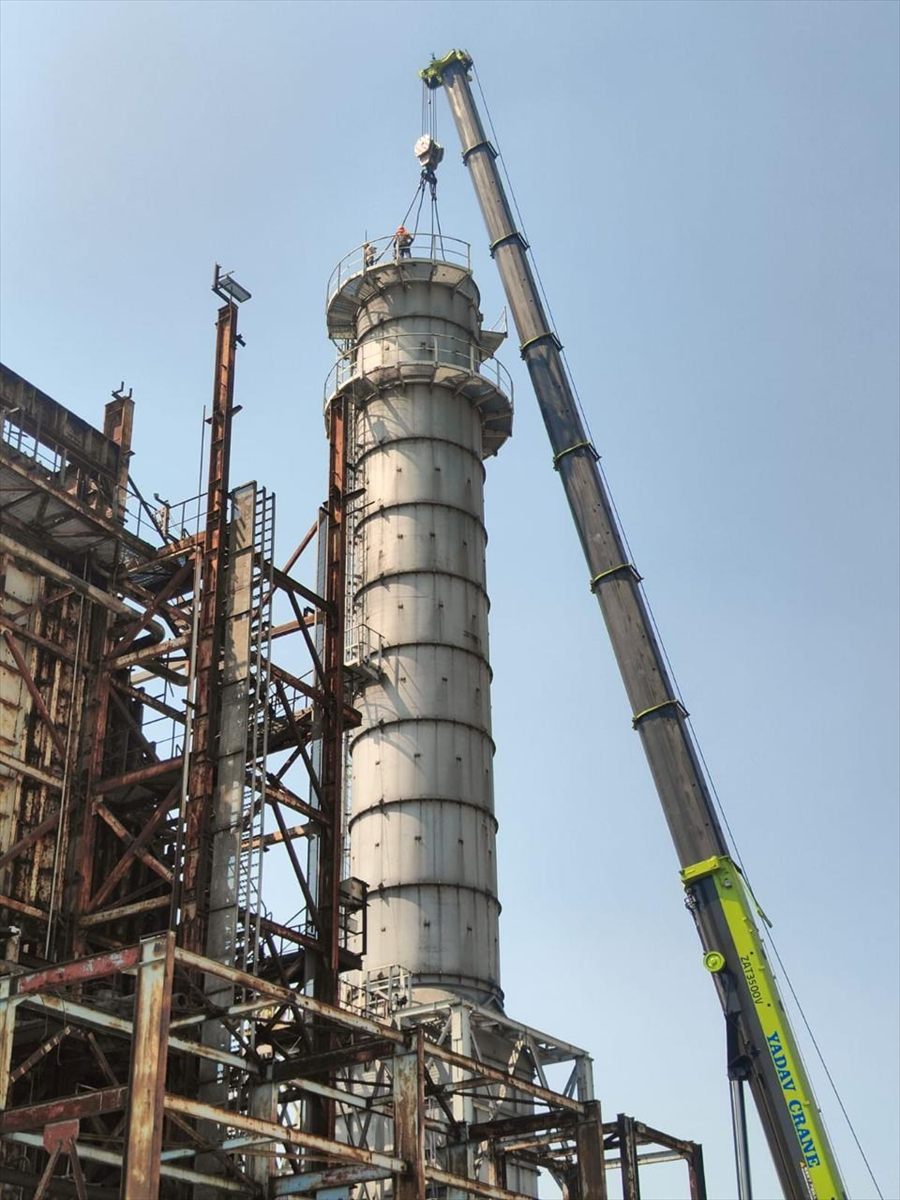 Distillation column being erected on site by crane
