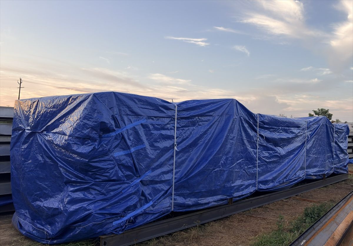 Long machinery run under tarpaulin at dusk sealed for the night
