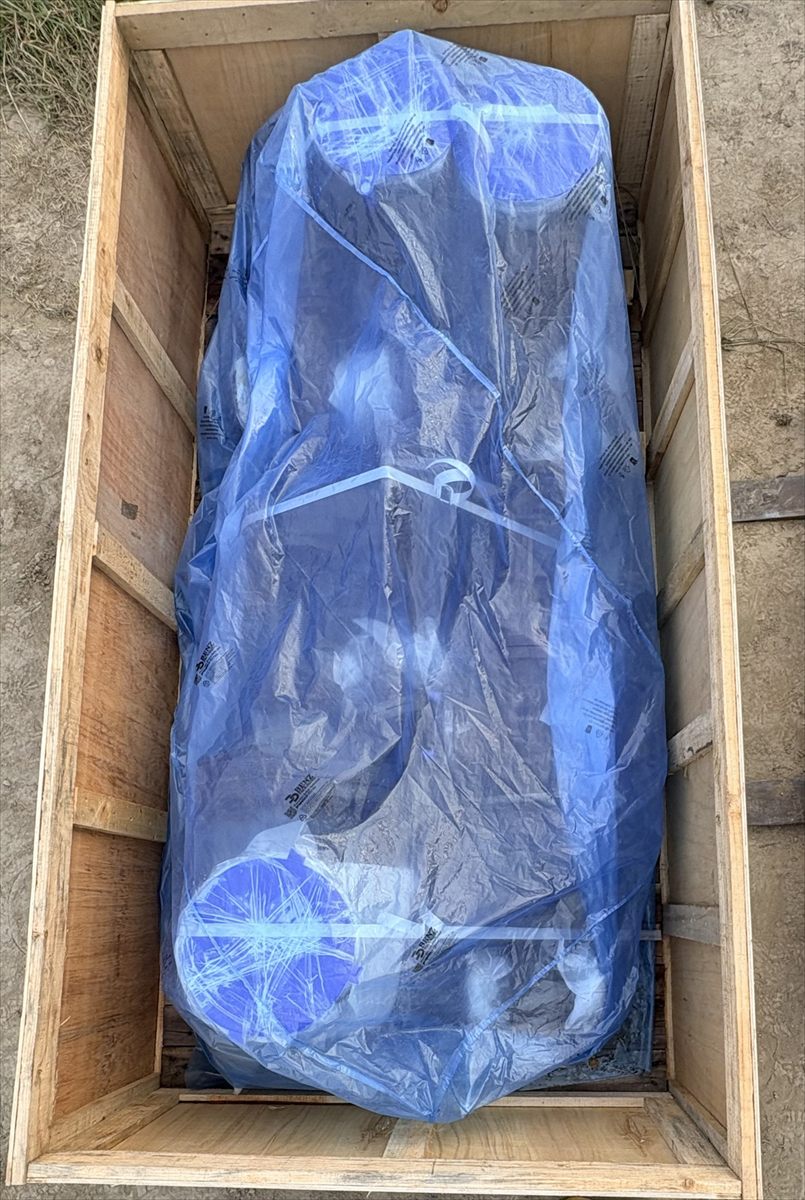Machine seated inside a wooden export crate, wrapped and blocked before closure