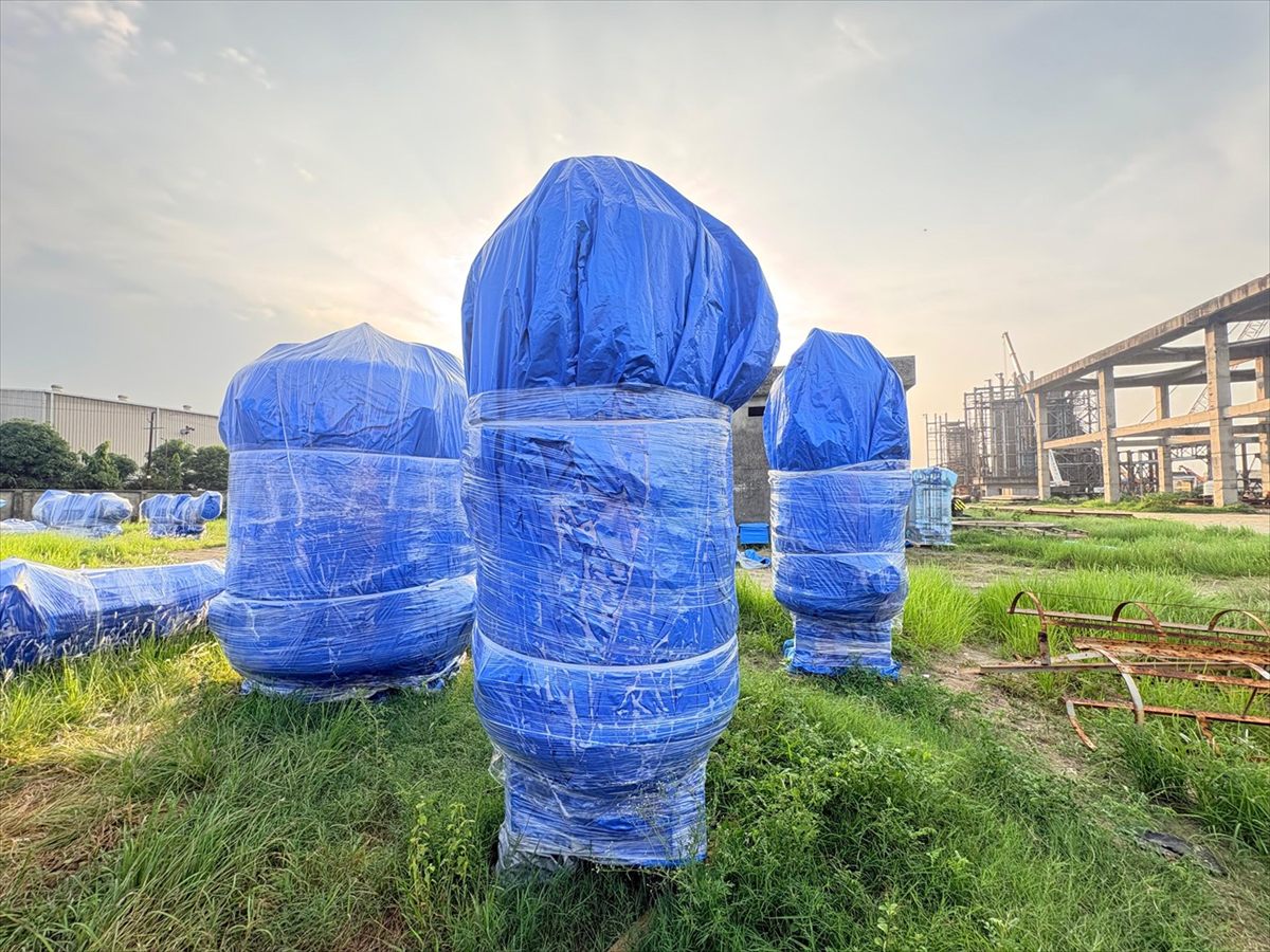 Wrapped process vessels standing in a laydown yard at sunrise, Pune