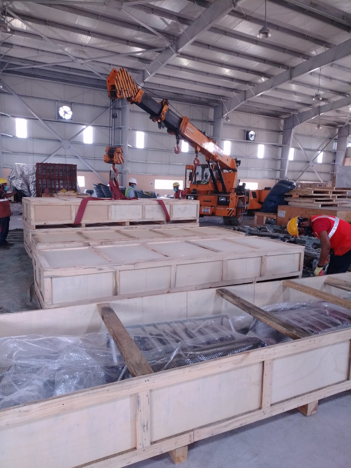 Crane lifting a crated heavy machine at a customer OEM facility